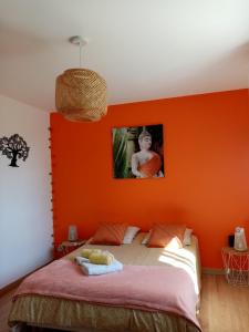 ein Schlafzimmer mit einer orangefarbenen Wand und einem Bett in der Unterkunft Le chêne blanc in La Genétouze