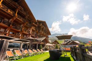 a resort with chairs and umbrellas on the lawn at Hôtel Au Chamois d'Or by Les Etincelles in L'Alpe-d'Huez