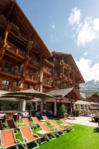 a group of chairs and umbrellas in front of a building at Hôtel Au Chamois d'Or by Les Etincelles in L'Alpe-d'Huez