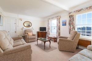 a living room with chairs and a table and a tv at Upper Instow Beach Cottage in Instow