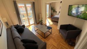 a living room with a couch and a television at 4 Newly Renovated Charming Apartments steps from Panormou Metro Station in Athens