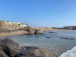 a beach with rocks in the water and people on the beach at Ploedle Lodge, Cosy holiday letting, near Bude. in Bridgerule