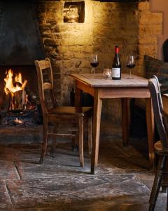 a wooden table with two glasses of wine and a fireplace at The Ebrington Arms in Chipping Campden +40 photos