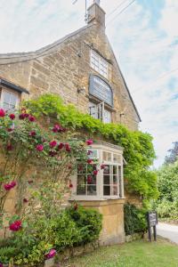 a brick building with flowers on the side of it at The Ebrington Arms in Chipping Campden