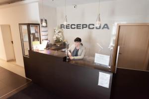 a person sitting at a counter in a office at Twój Hostel Klimczoka 7 in Katowice