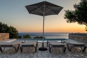 a pool with two chairs and an umbrella at Boutique Villa Olivia in Agios Pavlos