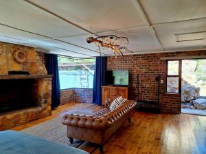 a living room with a couch and a fireplace at Trout Cottage in Paarl