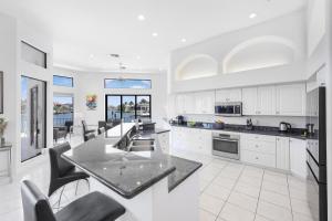 Una cocina con gabinetes blancos y una encimera negra. en Waterfront home on key lot with pool, spa and views, en Marco Island