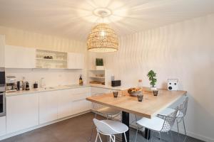 une cuisine avec une table en bois et des armoires blanches dans l'établissement La Petite Maison Dans la Prairie - Havre de paix, à Rennes 8 autres photos