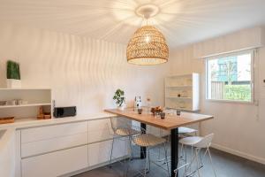 une cuisine avec une table, des chaises et un éclairage dans l'établissement La Petite Maison Dans la Prairie - Havre de paix, à Rennes