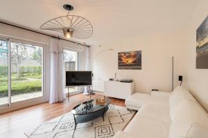 un salon avec un canapé blanc et une télévision dans l'établissement La Petite Maison Dans la Prairie - Havre de paix, à Rennes