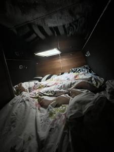 duas crianças deitadas numa cama num quarto escuro em Waterside campervan em Manchester