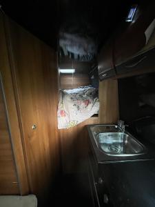 uma pequena cozinha com um lavatório e uma cama em Waterside campervan em Manchester