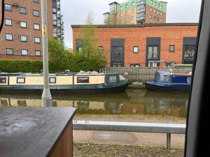 two boats are docked in a canal with buildings at Waterside campervan in Manchester