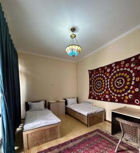 Cette chambre comprend deux lits et un lustre. dans l'établissement Suzani National House, à Boukhara