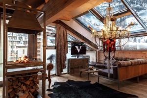 a living room with a fireplace and a chandelier at Backstage Boutique SPA Hotel in Zermatt