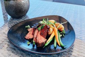 a plate of food with meat and vegetables on a table at Boutique-hotelli Vellamo - Lehmonkärki Resort in Asikkala +48 photos