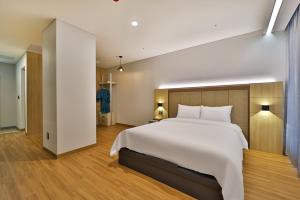 a bedroom with a large white bed and wooden floors at Gimhae City Hotel in Gimhae