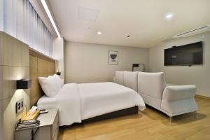 una camera d'albergo con un letto bianco e una sedia di Gimhae City Hotel a Gimhae