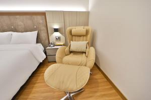 a hotel room with a chair and a bed at Gimhae City Hotel in Gimhae