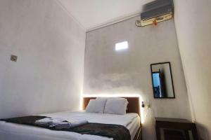 a bedroom with a bed in a room with a mirror at OYO 93867 Minso Inn Sepanjang in Yogyakarta