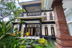 a house with a balcony and a brick pillar at Capital O 93844 Arta Adi Homestay in Bangli