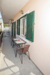a table and chairs on a balcony with green shutters at A4 - Rosemary Apartment in Nydri
