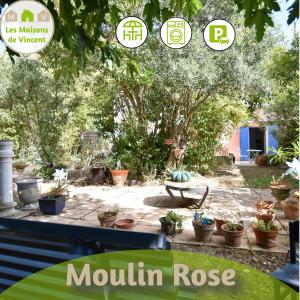 een tuin met potplanten en een bord dat berginroos leest bij Moulin Rose, Parking - Jardin in Arles