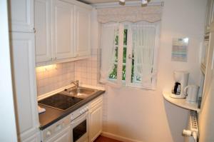 a kitchen with white cabinets and a sink and a window at Nordseestübchen Whg 05 in Nieblum