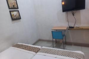 Pokój z łóżkiem, biurkiem i telewizorem w obiekcie Capital O 93872 Natura Guest House Syariah w mieście Purwokerto