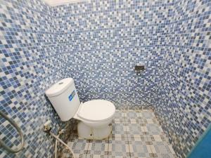 łazienka z toaletą w niebieskiej, wyłożonej kafelkami ścianie w obiekcie OYO 93870 Damai Guest House Cirebon w mieście Cirebon
