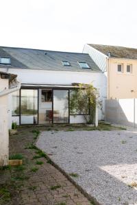 a house with glass doors and a gravel driveway at Les Frangines - maison de ville avec jardin Ault in Ault