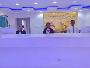un grupo de tres personas parados detrás de un mostrador en Global Signature Hotel and Resort, en Ibadán