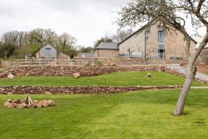 un patio con una pared de piedra y un edificio en The Linhay, Higher Yalberton Farm, en Paignton
