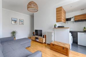 een woonkamer met een bank en een keuken bij Résidor - Warm and bright 4P apartment! in Boulogne-Billancourt