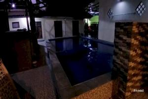 ein Haus mit einem Pool in einem dunklen Zimmer in der Unterkunft OYO 93861 Adinda Guest House Syariah in Garut