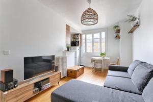een woonkamer met een bank en een flatscreen-tv bij Résidor - Warm and bright 4P apartment! in Boulogne-Billancourt