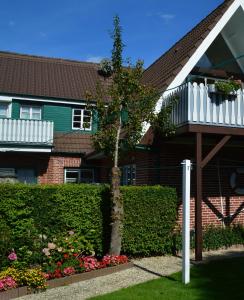 a house with a tree and flowers in the yard at Nordseestübchen Whg 04 in Nieblum