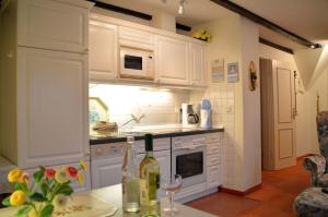 a kitchen with white cabinets and a table with wine bottles at Nordseestübchen Whg 04 in Nieblum