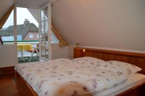 Una cama en un dormitorio con vista a un balcón. en Nordseestübchen Whg 04, en Nieblum