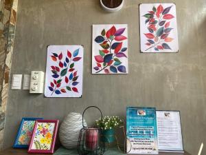 quatre peintures sur un mur avec des fleurs sur lui dans l'établissement Wilnags Inn Puerto Princesa near airport, à Puerto Princesa