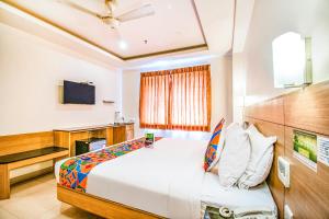 a hotel room with a bed and a tv at FabHotel Prime Royal Castle Gandhipuram in Coimbatore