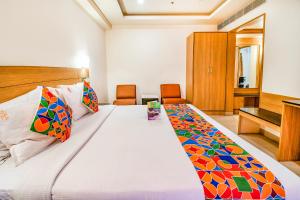 FabHotel Prime Royal Castle Gandhipuram في كويمباتور: غرفة نوم مع سرير كبير مع وسائد ملونة