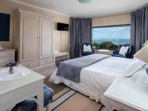 a bedroom with a large bed and a window at Sandbaai Country House in Hermanus