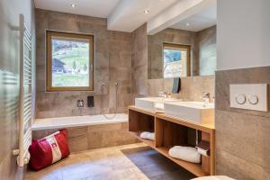 uma casa de banho com 2 lavatórios, uma banheira e um chuveiro em Mallaun Hotel.Erlebnis em See