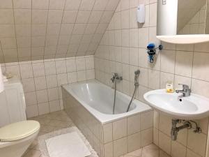 a bathroom with a tub and a sink and a toilet at Gösser BACHGASSLHOF -- Bed and Breakfast -- Apartments in Leoben