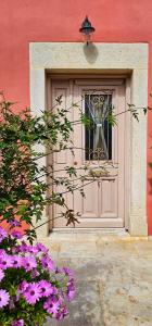 a door of a building with a window and purple flowers at Villa Arhontiko In Arhanes in Archanes