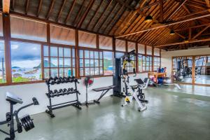a gym with treadmills and machines in a room with windows at Dragon Dive Komodo Dive Resort in Labuan Bajo
