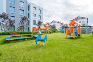 um parque infantil num jardim relvado em frente a um edifício em Apartamenty NCNK przy Marinie w Kątach Rybackich em Kąty Rybackie