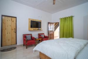 ein Schlafzimmer mit einem Bett, 2 Stühlen und einem TV in der Unterkunft Jaavi Homestay Nainital in Nainital